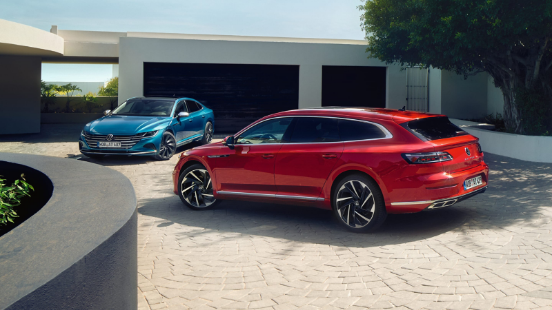 Un Arteon azul y otro rojo aparcados delante de una casa