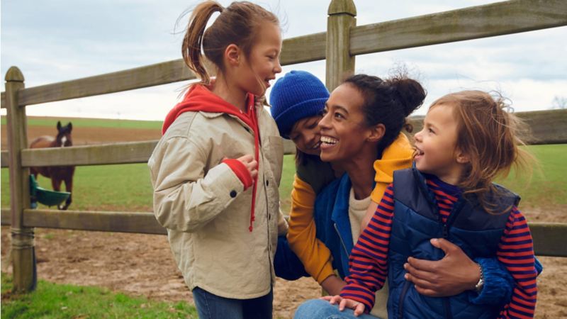 Una mujer con tres niños sonriendo en el campo.