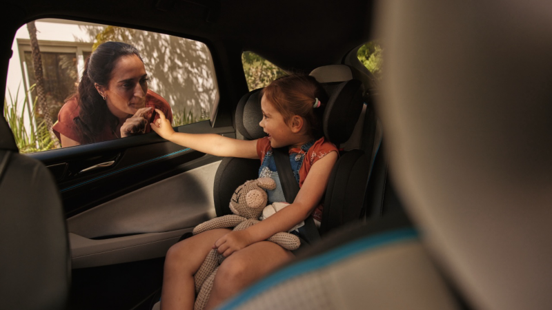 Una niña dandole la mano a su madre a través de la ventanilla de un Volskwagen