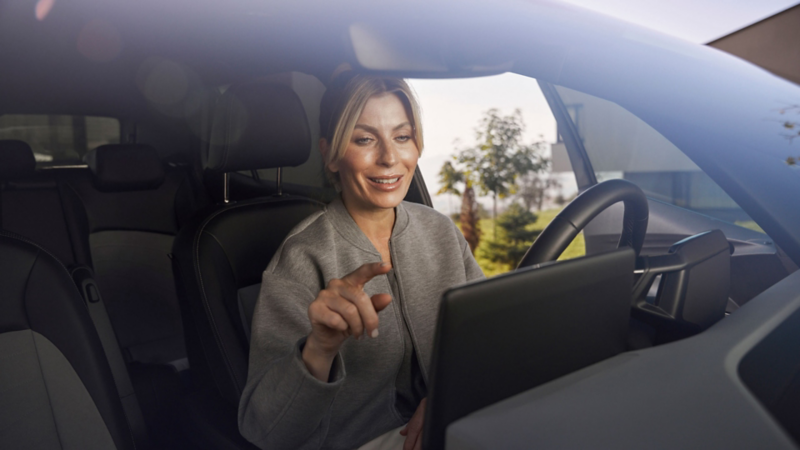 Una mujer al volante de un Volkswagen usando la pantalla interactiva del salpicadero