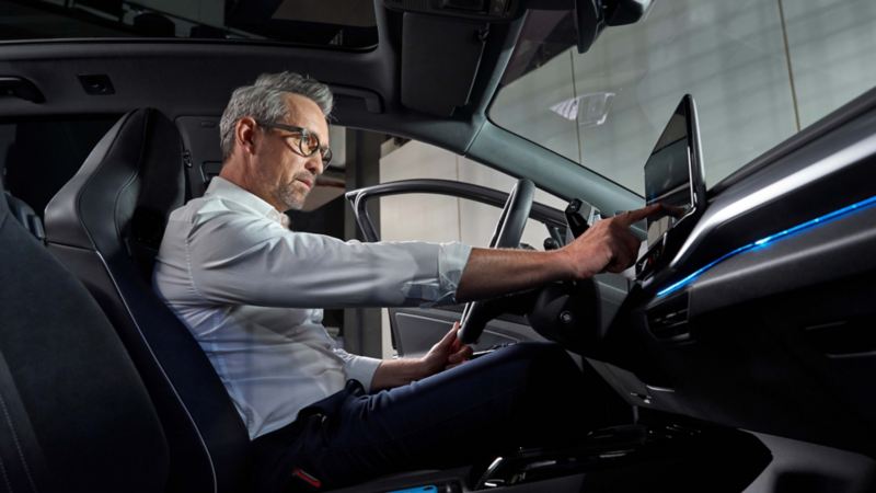 Hombre al volante de un Volkswagen usando la pantalla interactiva del salpicadero