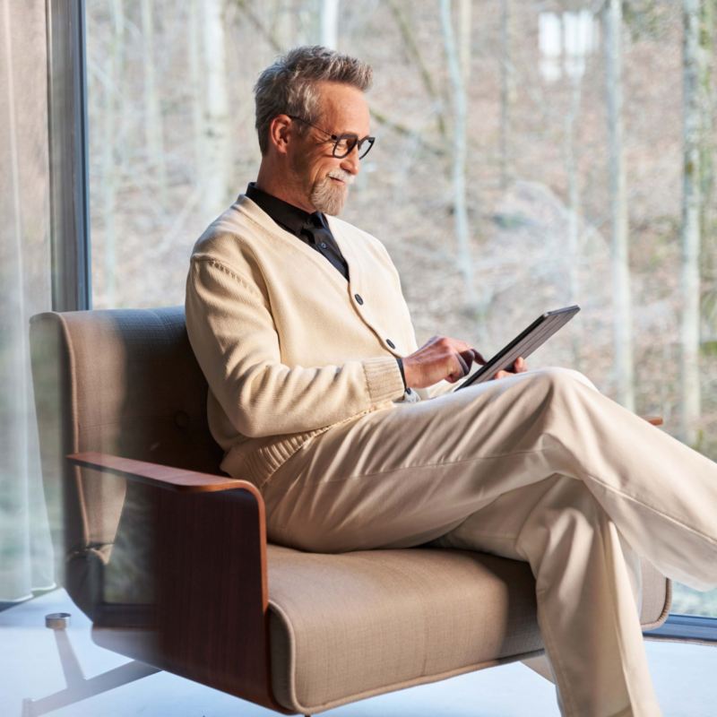 Un hombre sentando en un sillón en casa mirando una tablet