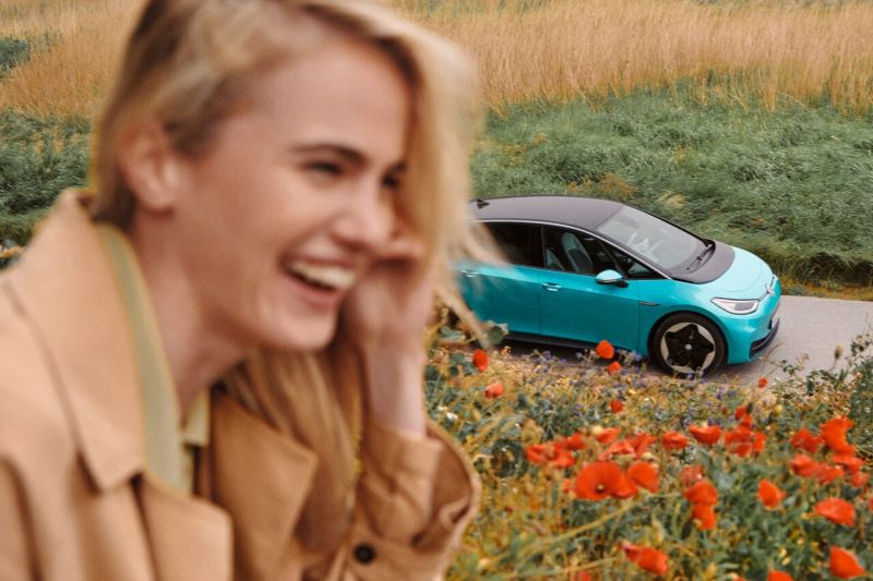 Volkswagen ID.3 esmeralda en un campo de flores y una chica sonriendo en primer plano