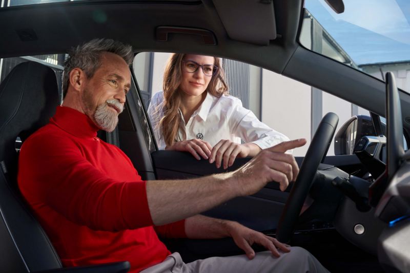 Un hombre al volante de un Volkswagen ID. y una agente de servicio hablándole a través de la ventanilla
