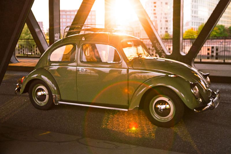 Volkswagen Betlle verde en un puente al ponerse el sol