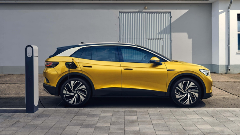 Volkswagen ID.4 amarillo visto de costado conectado a una estación de carga en la calle