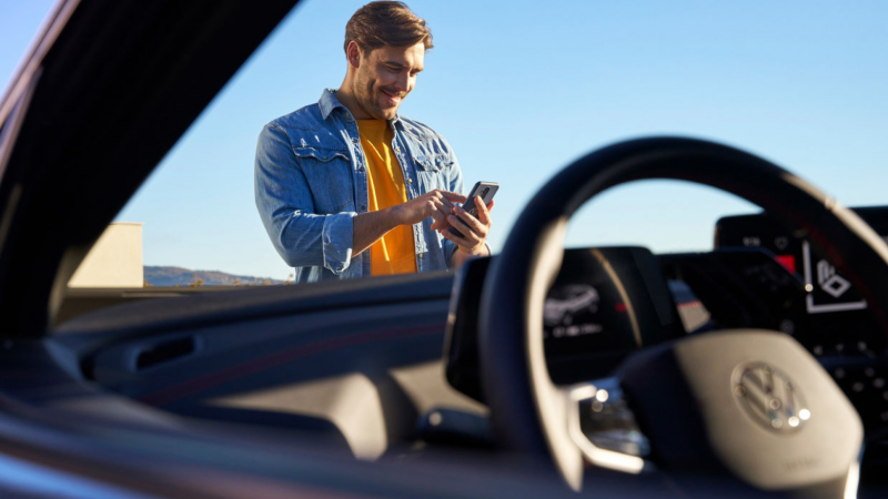 Un hombre con un smartphone visto desde el interior de un Volkswagen