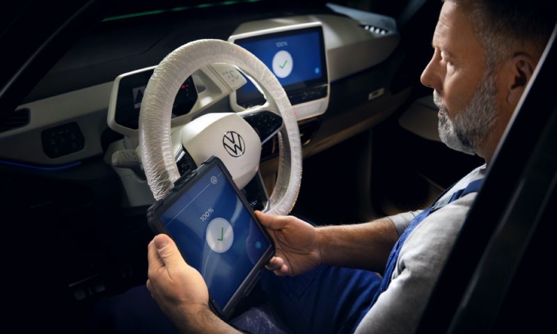 Mecánico con una tablet sentado al volante de un Volkswagen