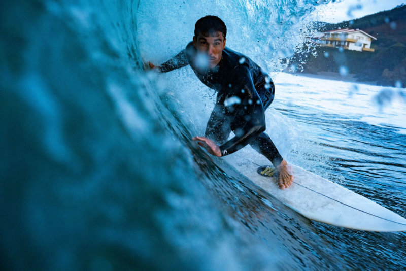 Primer plano de un surfista dentro de una ola con el neopreno The Roadcycled Wetsuit de Blue Banana