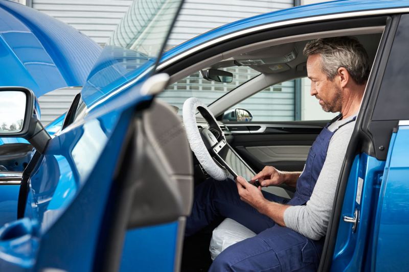 Un mecánico con una tablet sentado dentro de un Volkswagen
