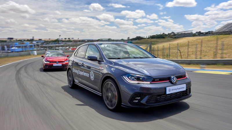 Dos coches Volkswagen circulando por un circuito cerrado con el logo de Driving Experience