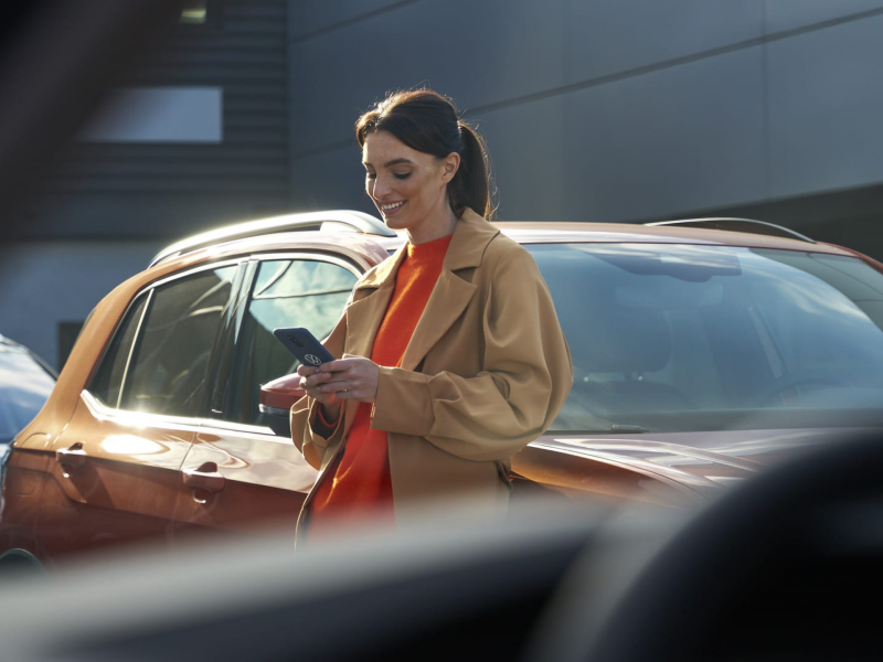 Una chica consultando el móvil apoyada en un Volkswagen