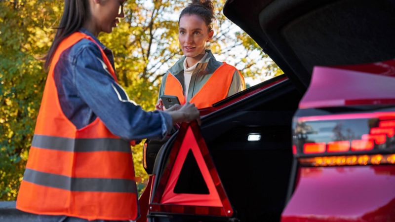 Dos chicas utilizando el triangulo de emergencia de un Volkswagen