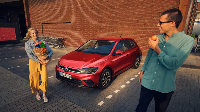 Una pareja junto a un Volkswagen rojo en el supermercado y el logo de My Way