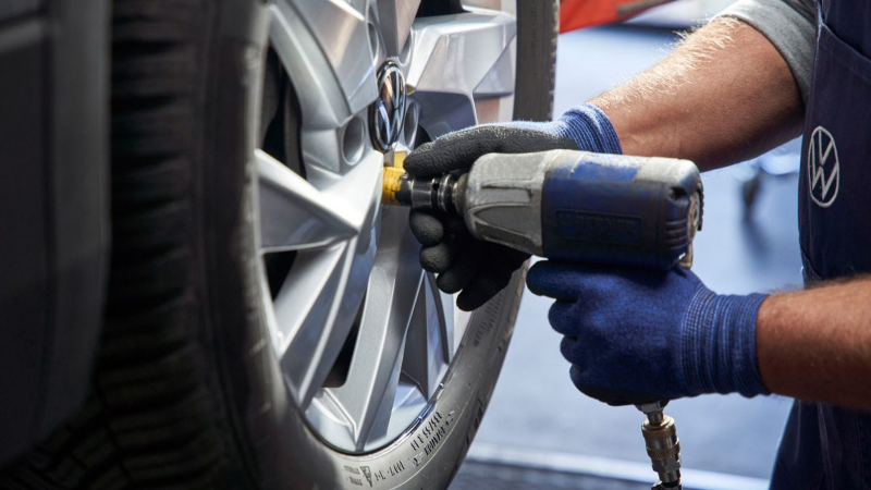 Detalle de un mecánico ajustando las tuercas de la llanta de un Volkswagen