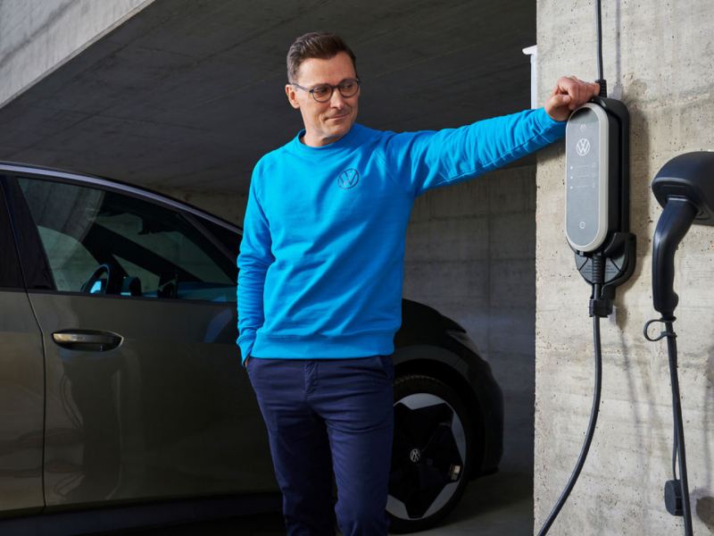 Un chico al lado de un cargador de pared de un Volkswagen eléctrico