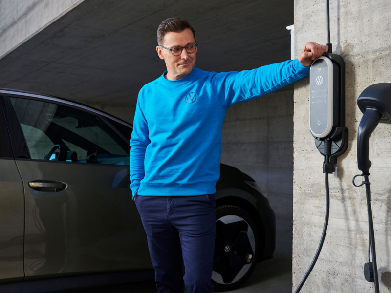 Un chico al lado de un cargador de pared de un Volkswagen eléctrico