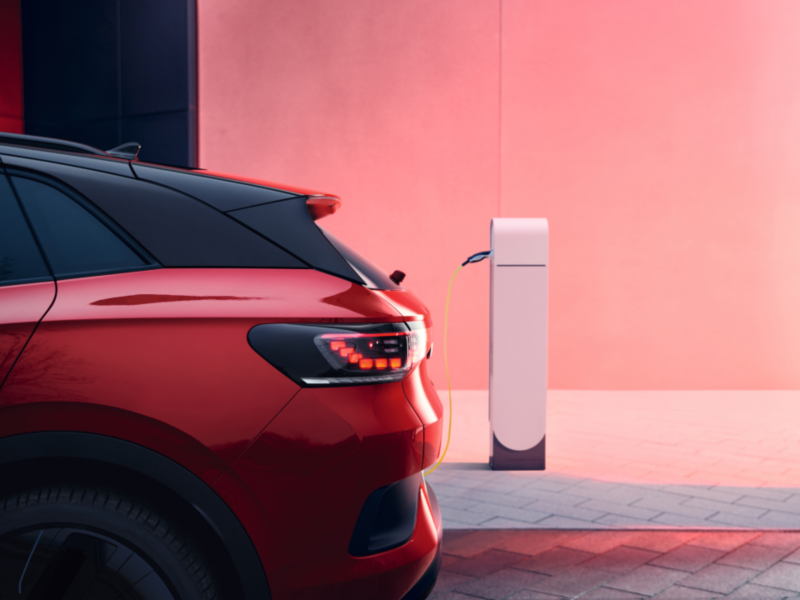 Un Volkswagen de color rojo eléctrico conectado a carga 