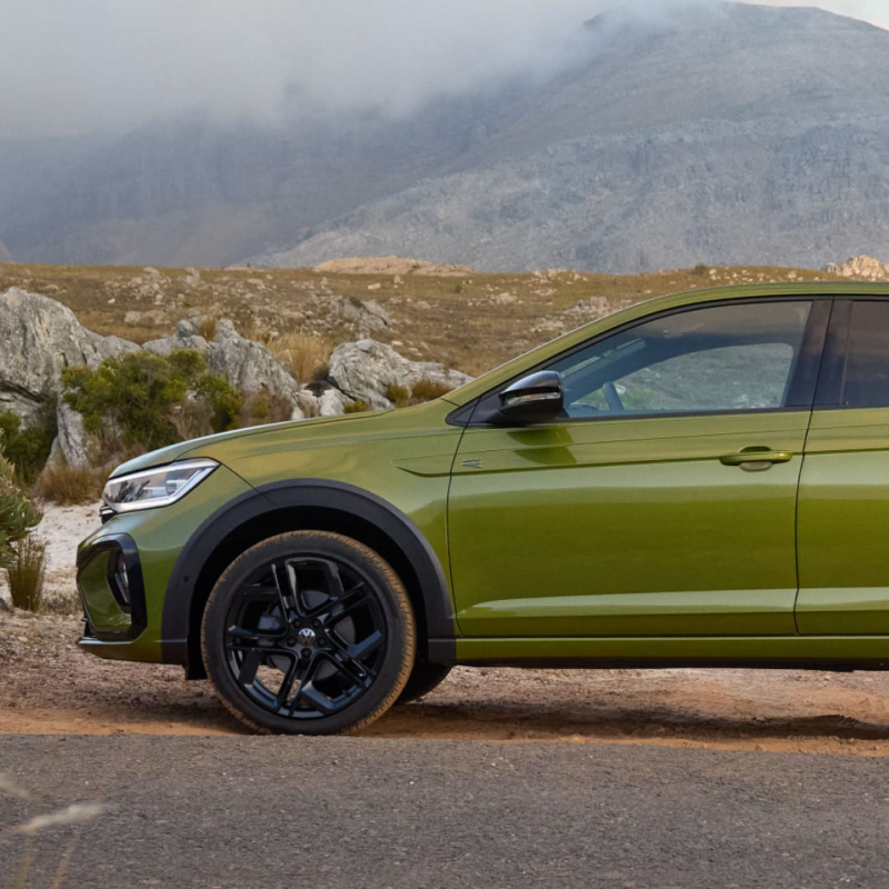 Vista lateral de un Volkswagen Taigo de color verde estacionado en una carretera