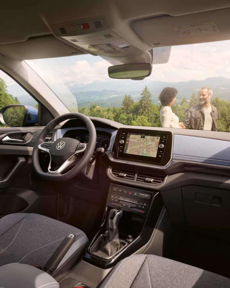 Interior del salpicadero de un Volkswagen T-Cross con una pareja en el exterior