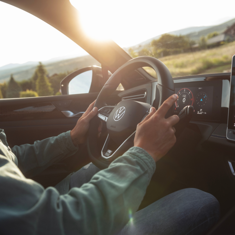 Detalle brazos de un hombre sujetando el volante de un Volkswagen Tiguan