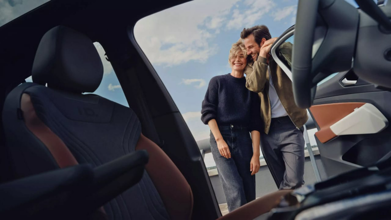 Una pareja sonriendo mirando el interior de un Volkswagen con Financiación