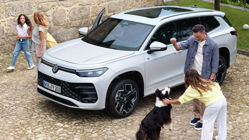 Una familia al lado de un Volkswagen de color blanco estacionado