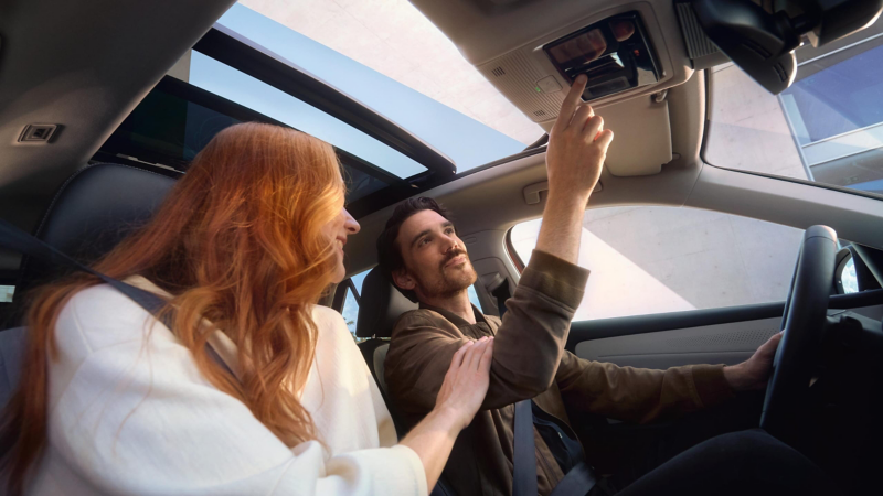 Una pareja sonriendo vistos desde el interior de un Volkswagen con la puerta abierta
