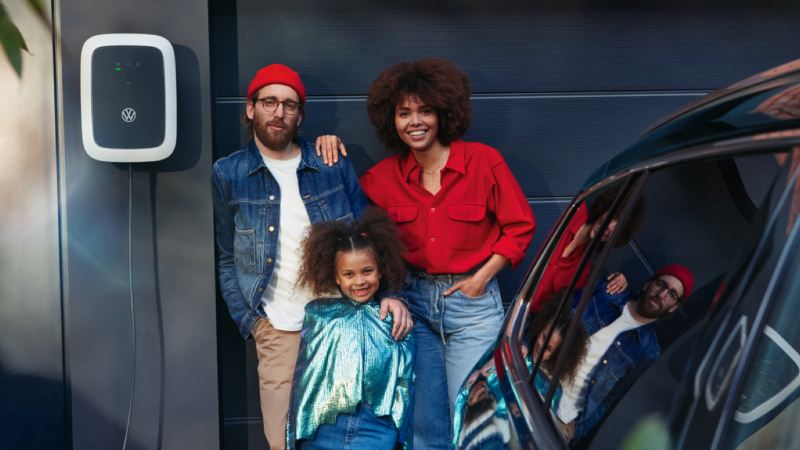 Una familia sonriendo junto a un coche y un Volkswagen ID. Charger