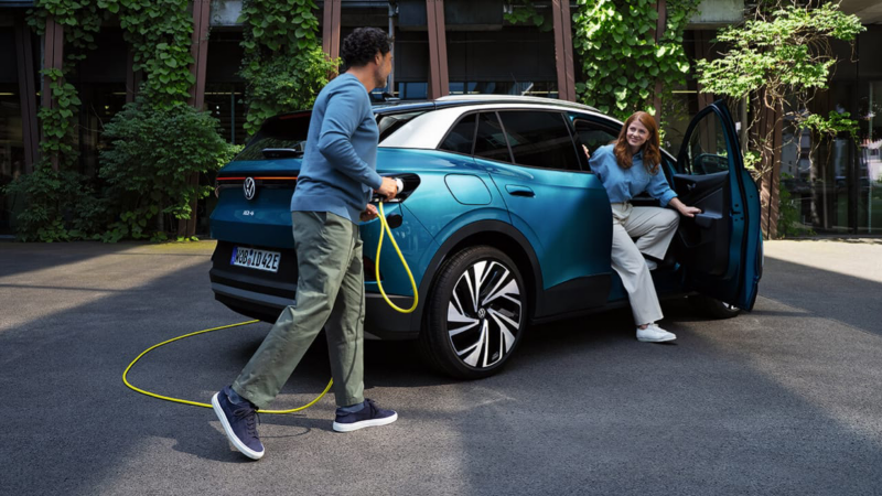 Un Volkswagen ID.4 azul atrás conectado a un cargador eléctrico en casa