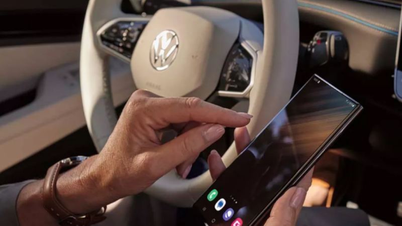 Detalle de la mano de una persona usando un móvil dentro de un Volkswagen ID.7