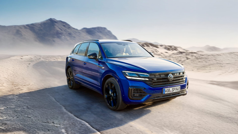 Un Volkswagen de color azul oscuro circulando por una carretera