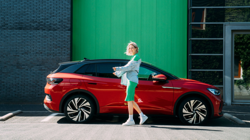 Mujer sonriendo delante de un Volkswagen ID.4 de color rojo.