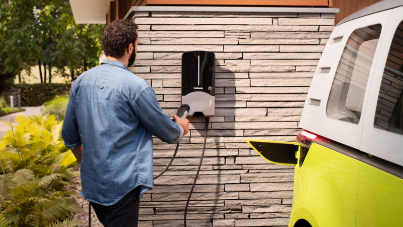 Un hombre con un Wallbox en casa y un Volkswagen ID. Buzz que se ve parcialmente