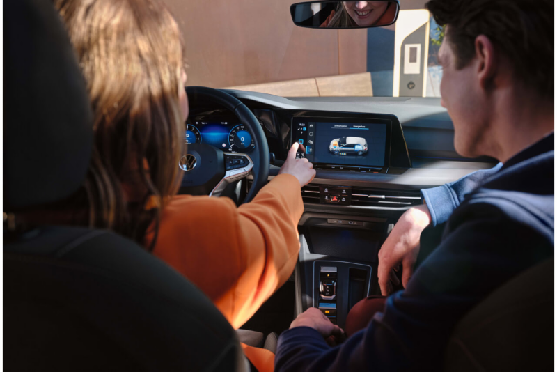 Pareja en el interior de un coche revisando los sistemas de carga de su Volkswagen.