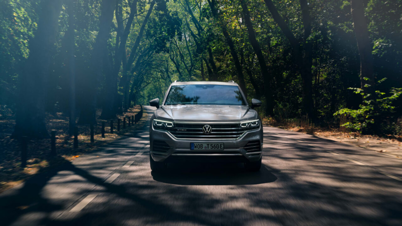 Volkswagen Touareg circulando por la carretera en medio del bosque.