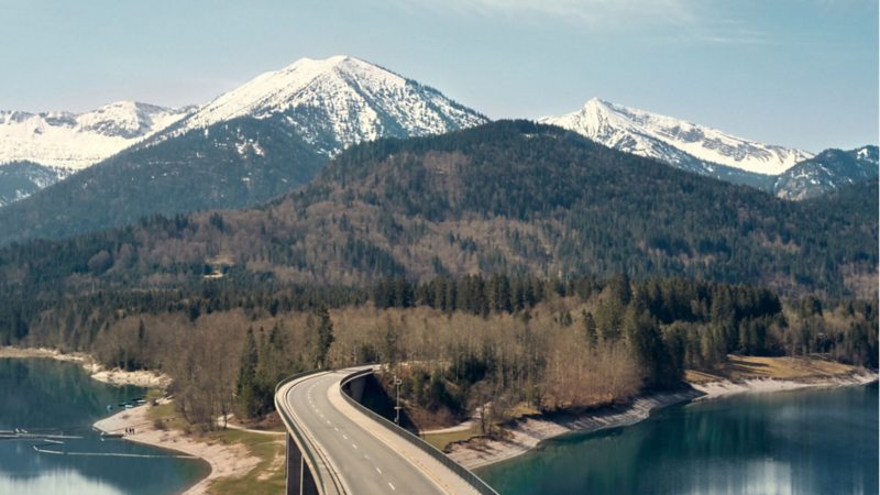 Paisaje una carretera con fondo de montañas nevadas.