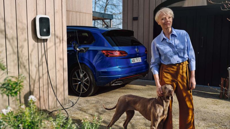 Mujer con un perro y un Volkswagen ID. cargando de fondo.
