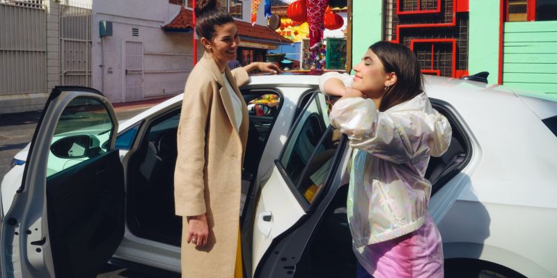 Dos chicas hablando de pie junto a un Volkswagen Golf eHybrid con las puertas abiertas