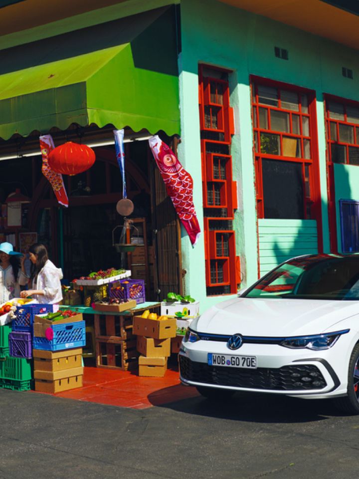 Volkswagen Golf 8 eHybrid blanco aparcado junto a un mercado chino