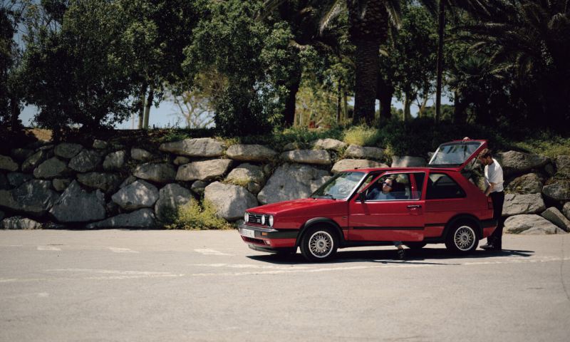 Una pareja en un Volkswagen Golf II rojo con las puertas abiertas