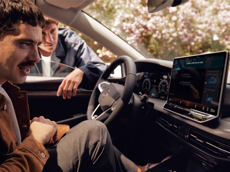 Un chico sentado al volante de un Volkswagen Golf usando el asistente de voz
