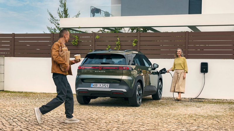 Una persona cargando su nuevo ID. Cross de VW mientras otra se acerca con cafés