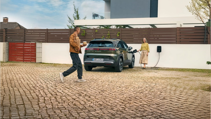 Una persona cargando su nuevo ID. Cross de VW mientras otra se acerca con cafés