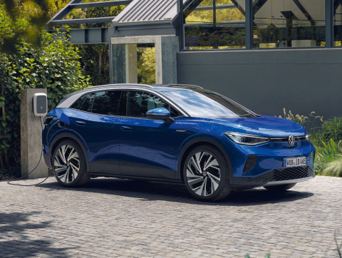 Volkswagen ID.4 azul aparcado en una casa y conectado al cargador eléctrico