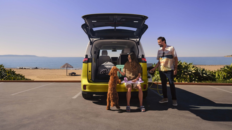 Una pareja con un perro en un ID. Buzz con el portón abierto en la playa