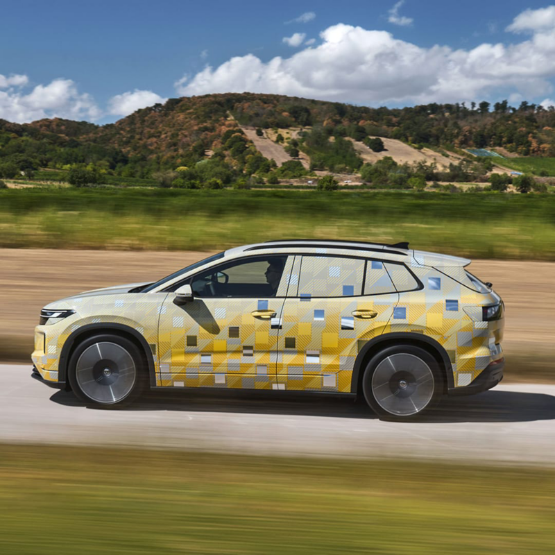 Un Volkswagen ID. Tiguan con camuflaje visto de costado en una carretera rural
