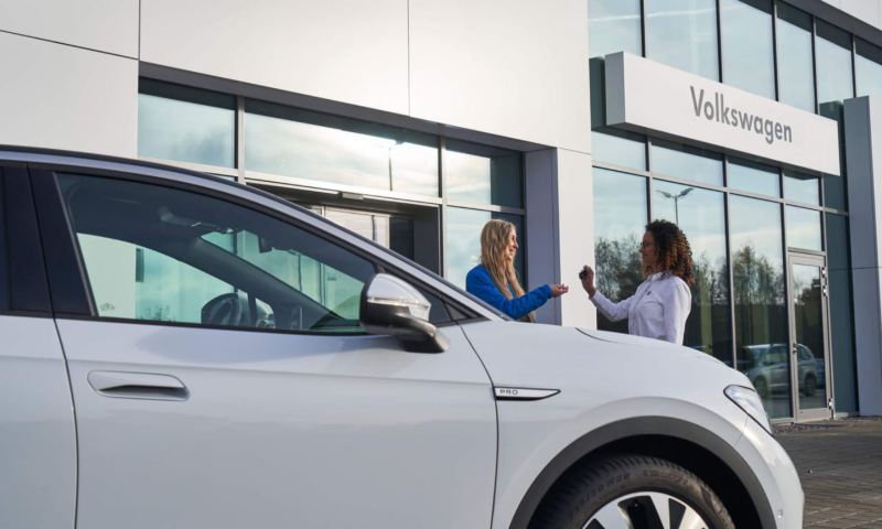 Una chica recibiendo las llaves de su coche en un concesionario Volkswagen