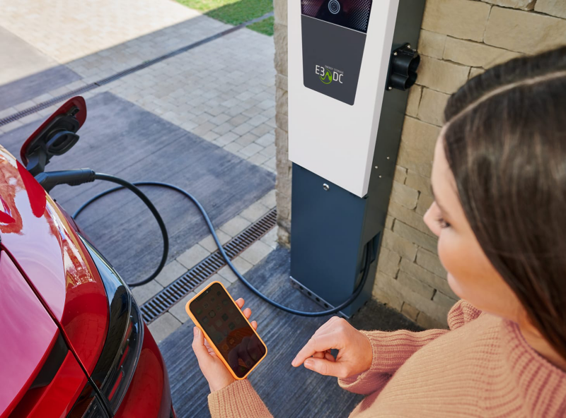 Plano cenital de una persona con un teléfono móvil en la mano mientras carga su ID.3 rojo en el garaje de su casa