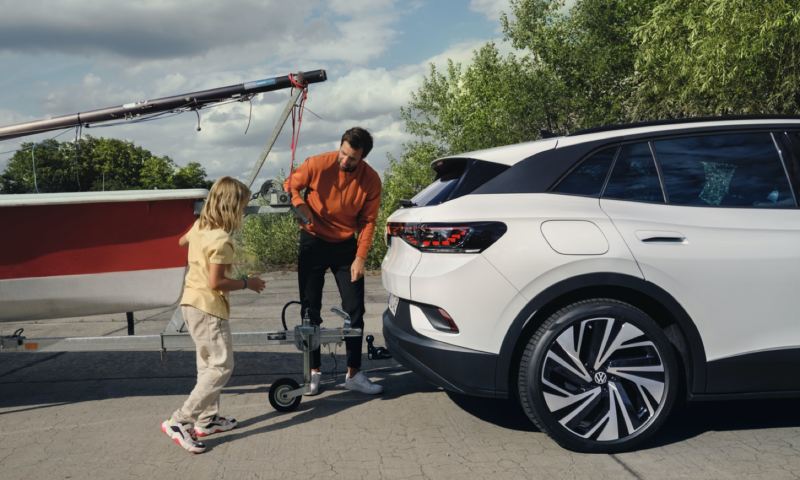 Un padre y una niña enganchando una lancha al remolque de un Volkswagen ID. 4